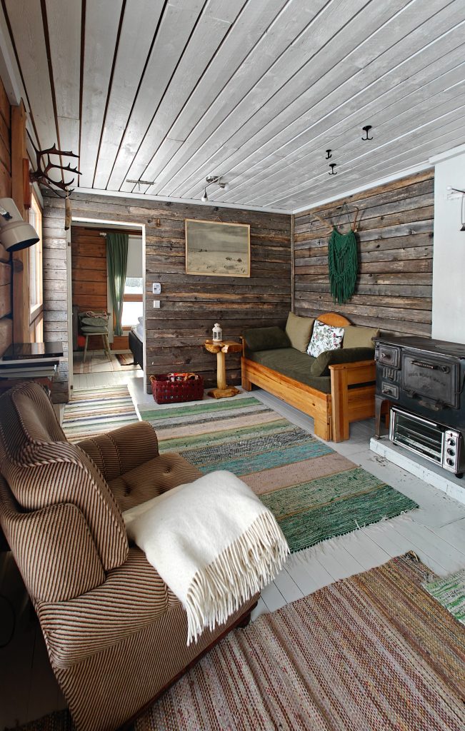 A bright and warm Kentura guesthouse, with numerous large windows letting in natural light. The interior features a cozy atmosphere, combining recycled materials and traditional Lapland elements in the design.
